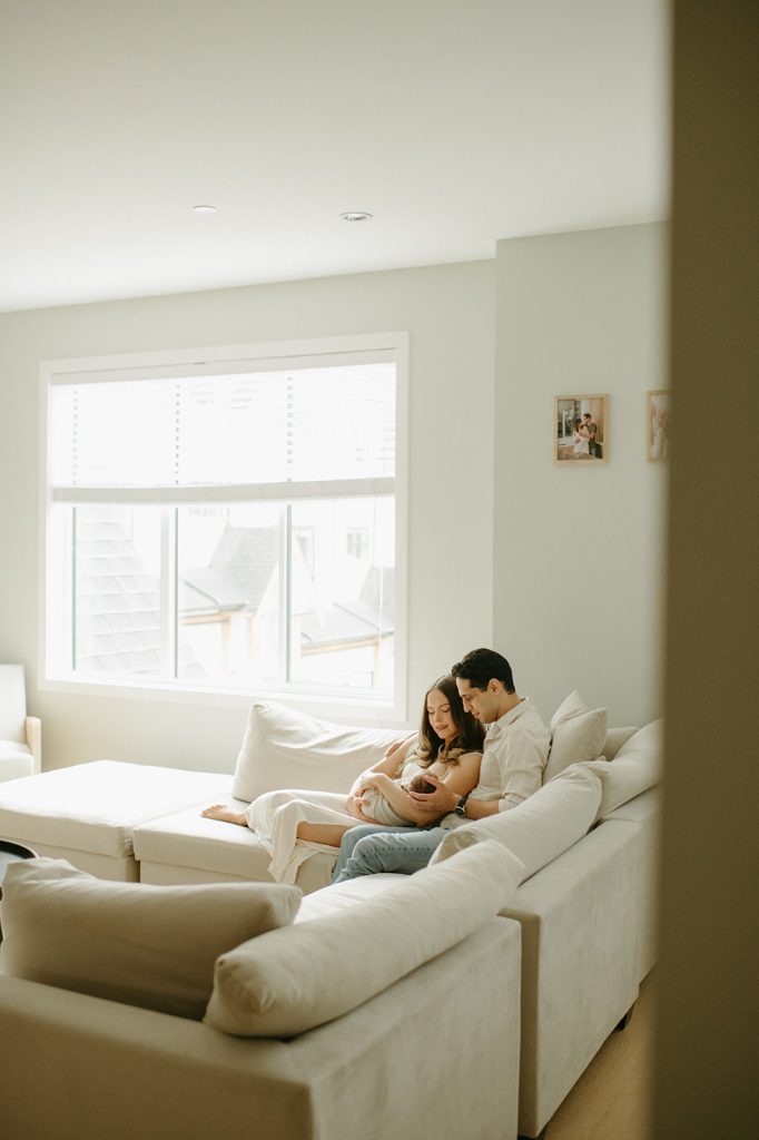 couple sitting on couch with newborn in home