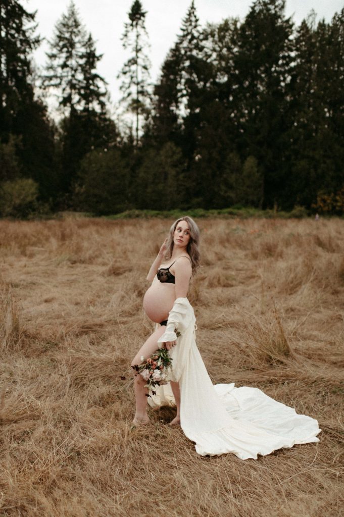 pregnant woman in grassy field in flowy dress and bouquet
