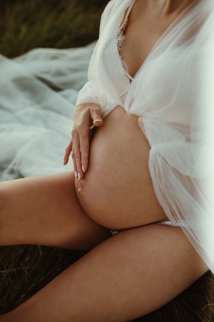 woman sitting on ground with pregnant belly