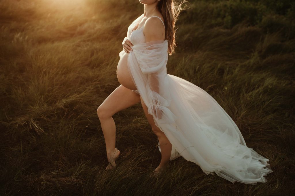 pregnant belly at sunset in grass