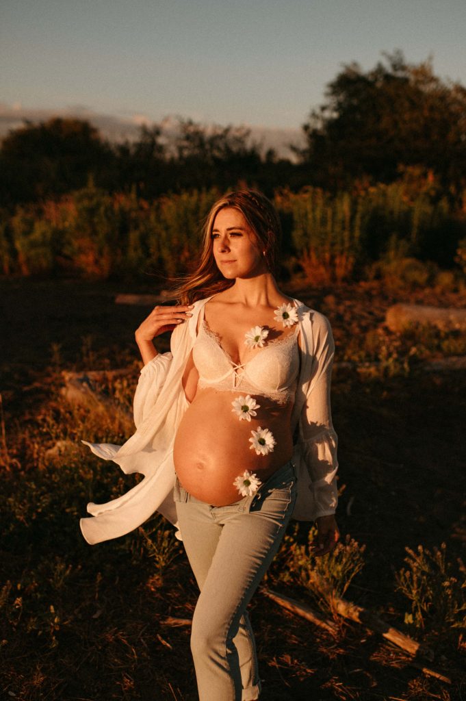pregnant woman in glowing light with flowers on stomach