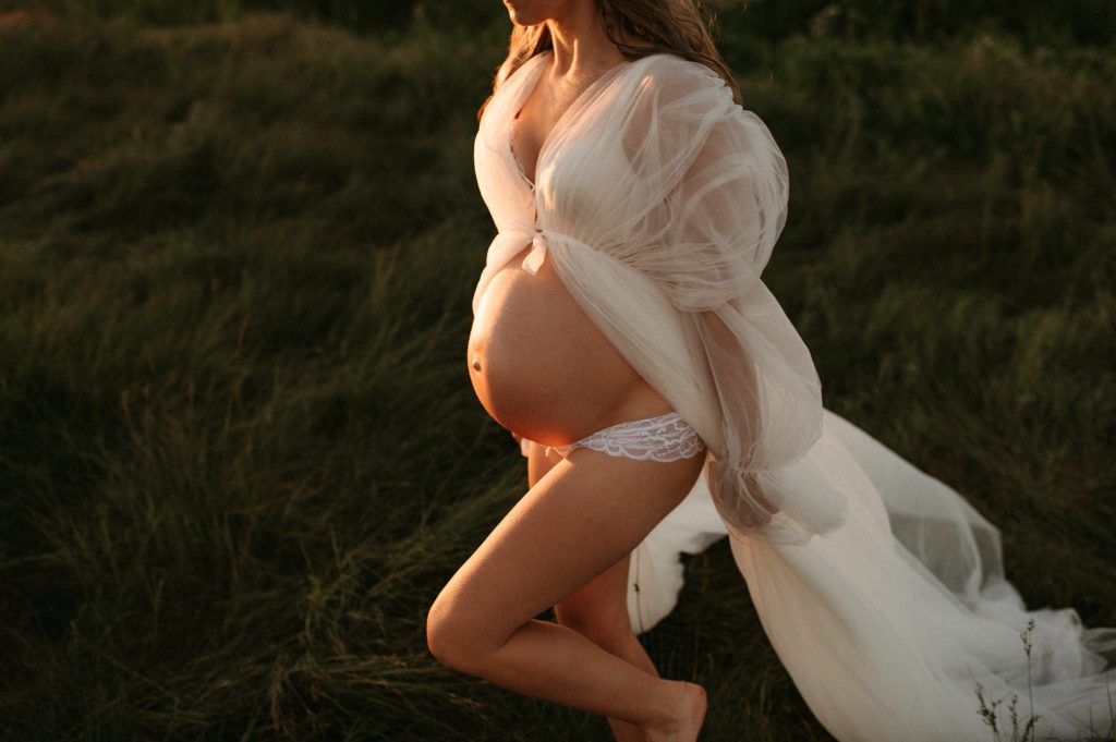 pregnant belly at sunset walking on grass