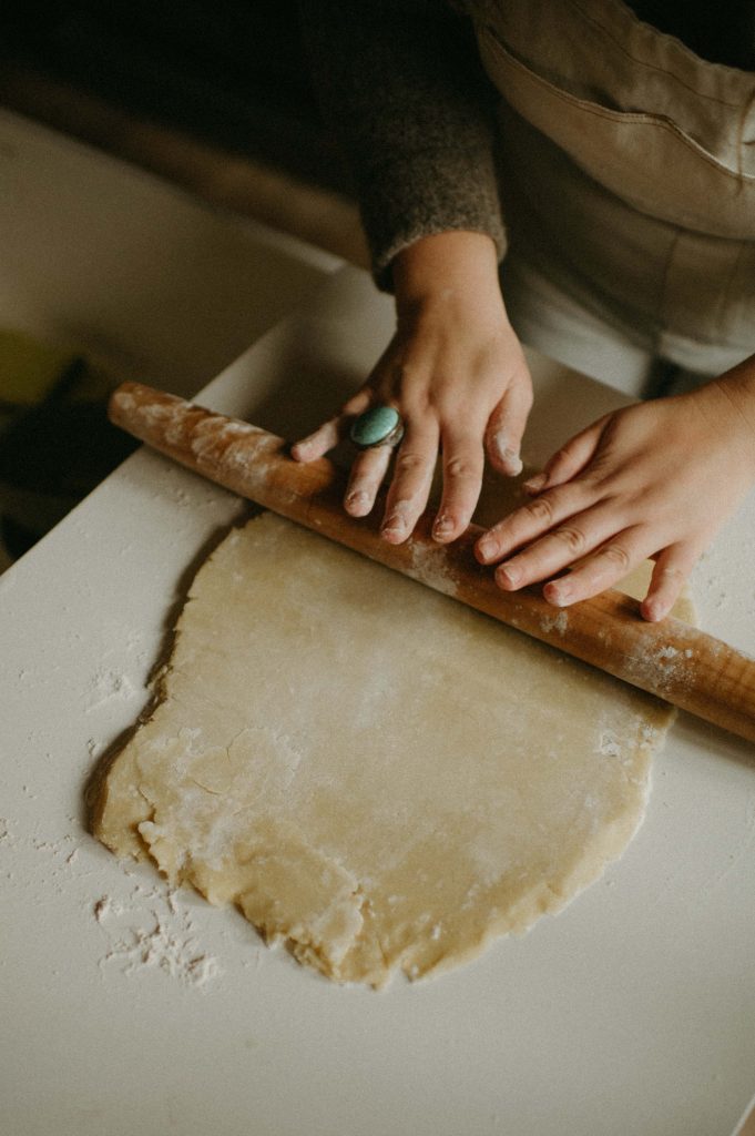 hands rolling dough with rolling pin