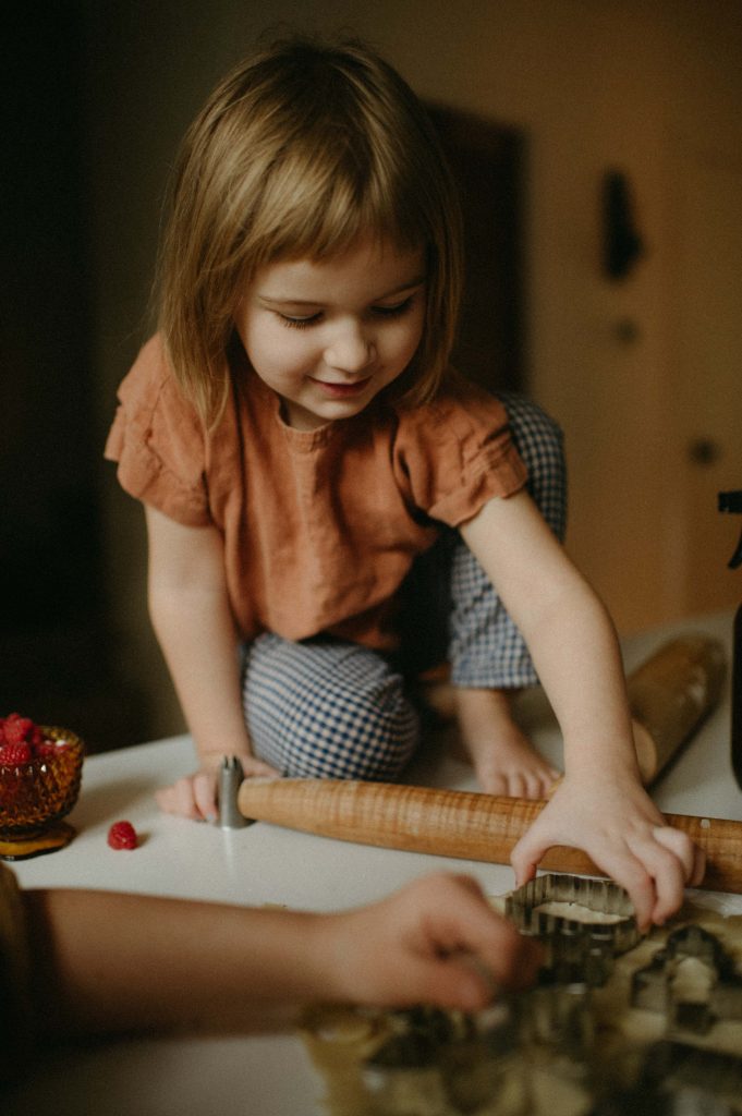 little girl on counter cutting cookie shapes
