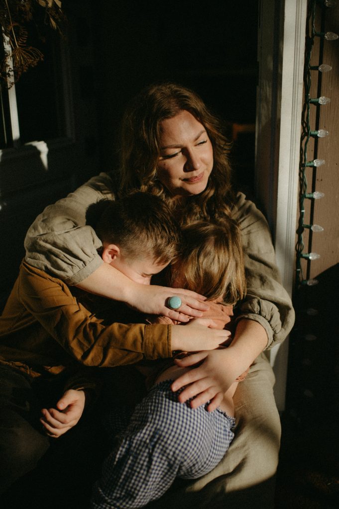mom hugging son and daughter in golden light