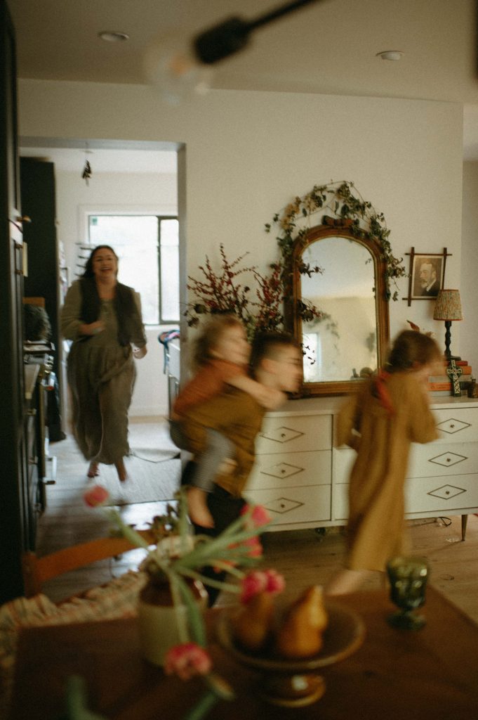 children running and playing in home with mother behind