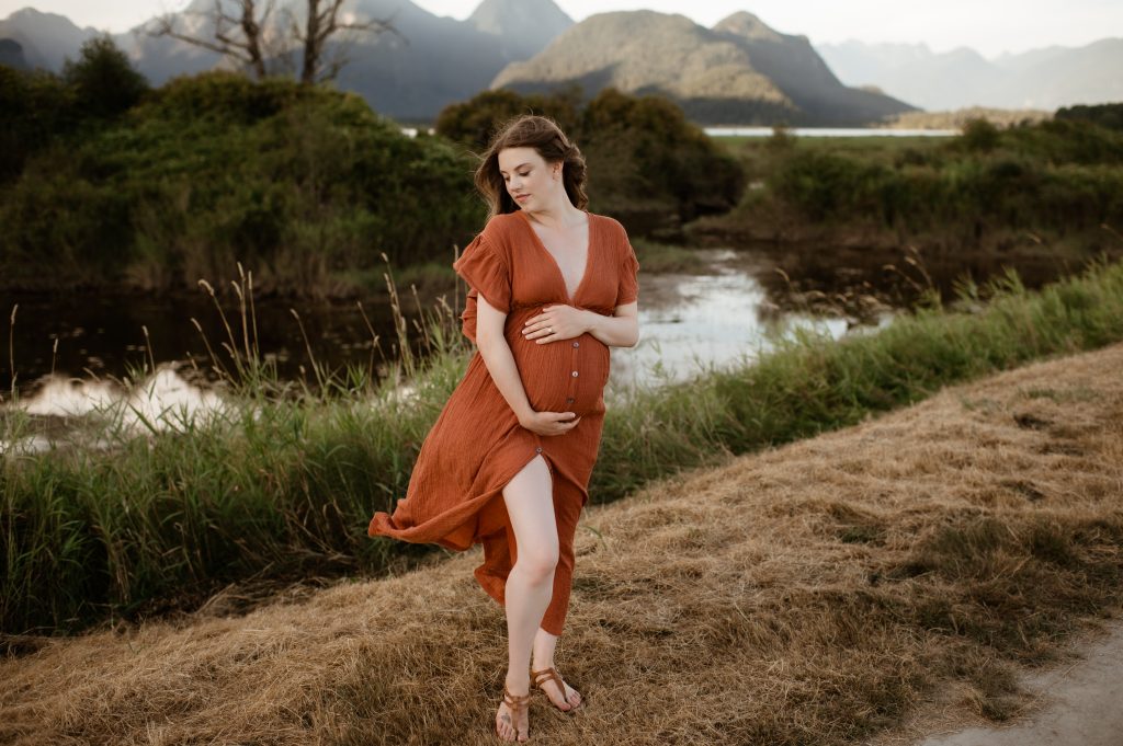 pregnant woman standing in front of mountains